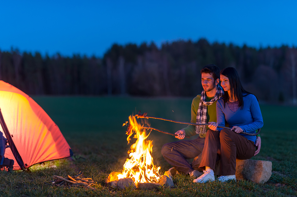 Couple roasting marshmallows over campfire